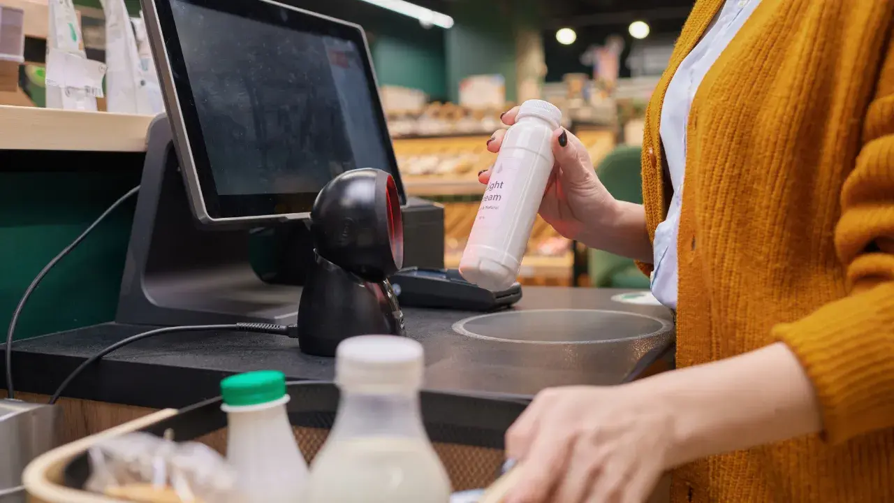 A cashier in the supermarket, using a POS system to scan a product